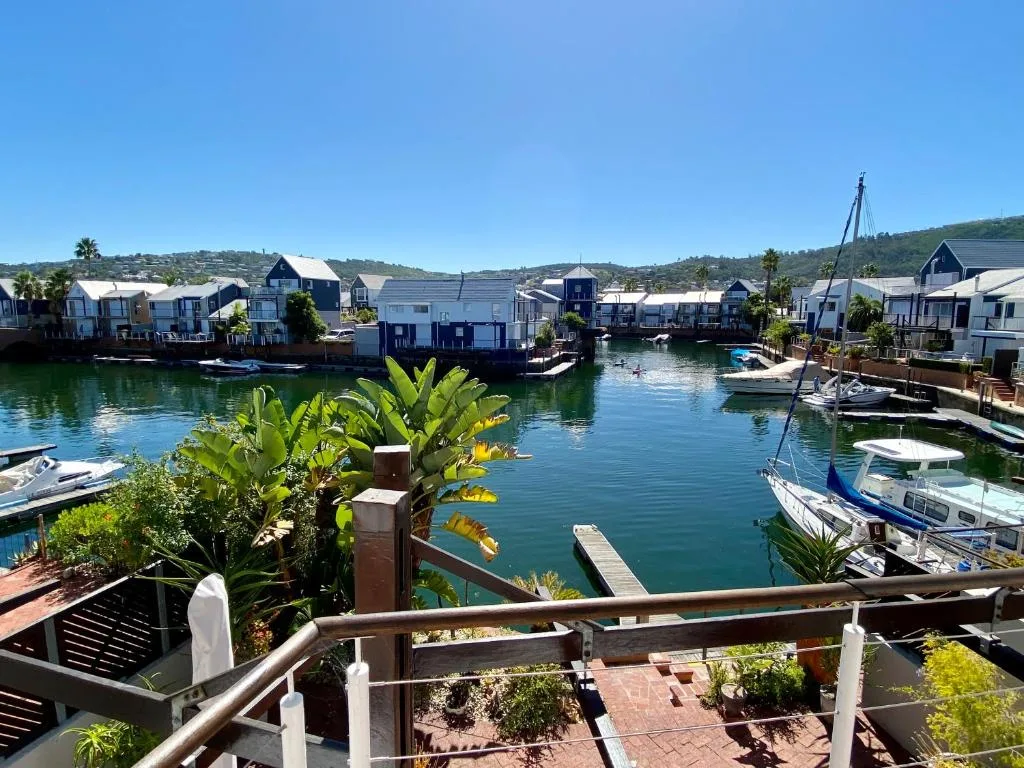 Turquoise lagoon with moored boats and waterfront houses under clear sky
