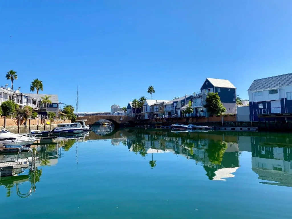 Serene waterfront village with colorful boathouses and calm lagoon reflections