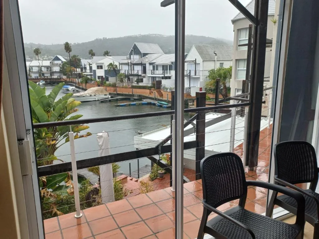 Knysna waterfront view with lagoon, boats, and surrounding houses from deck