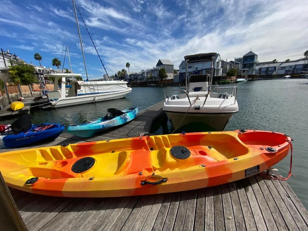 Colorful kayaks moored at wooden dock with waterfront boats and lagoon views