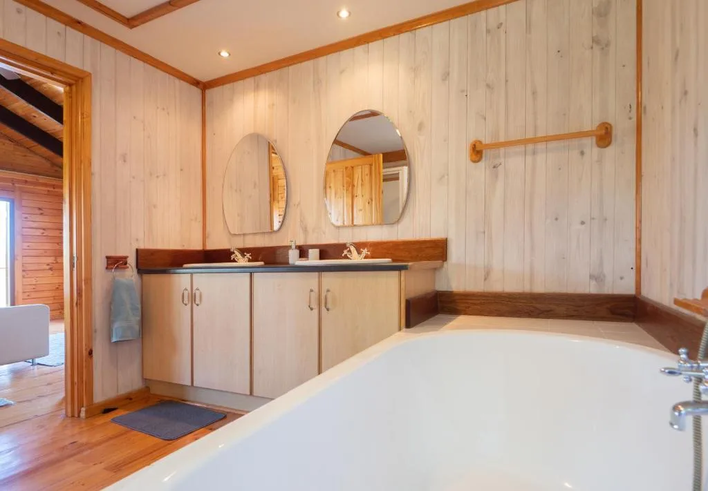 Spacious bathroom with dual vanity, large soaking tub, and wooden accents