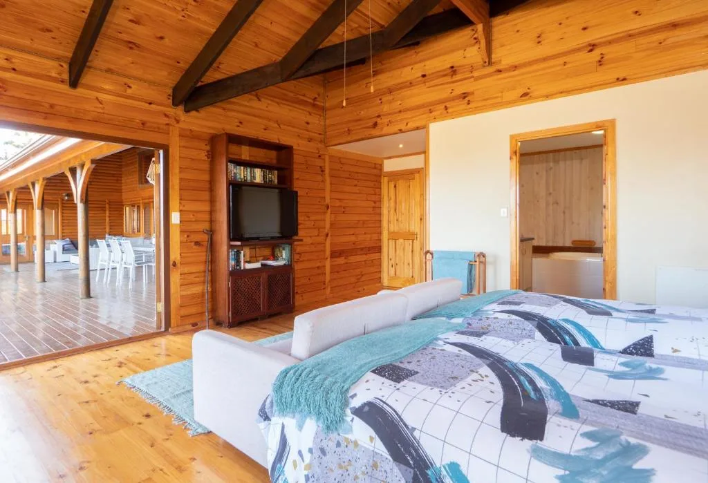 Spacious bedroom with wooden walls and high beamed ceiling in log cabin