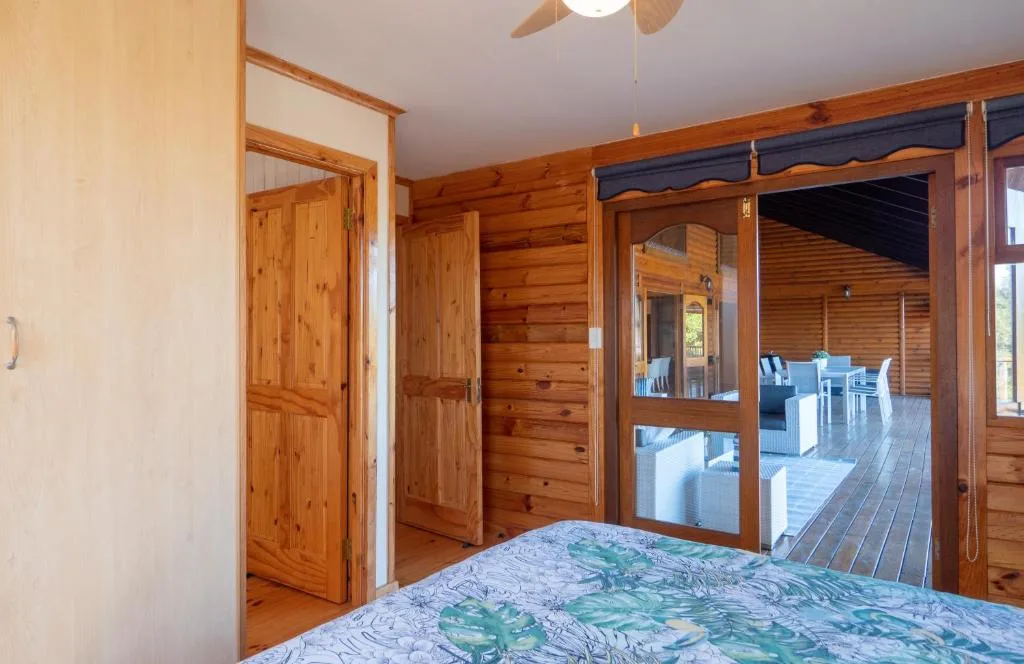 Wooden bedroom with glass doors opening to a deck area