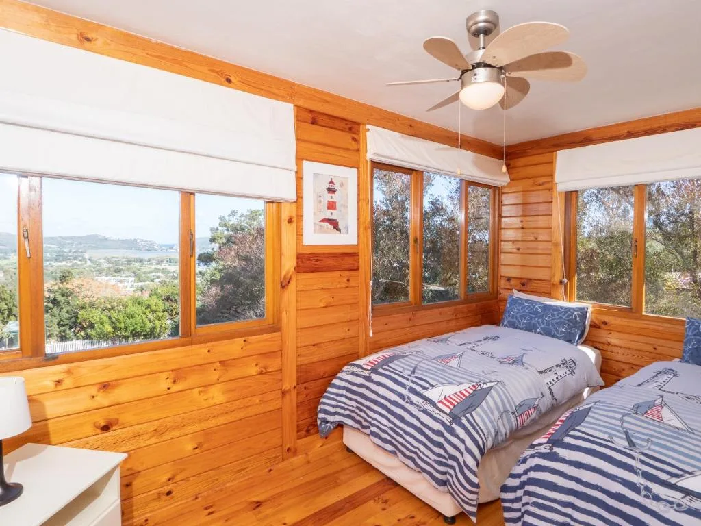 Wooden bedroom with two beds and panoramic windows overlooking green landscape