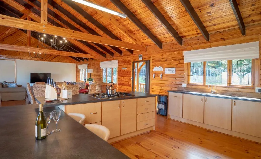 Open-plan kitchen with wooden cabinetry and dark countertops in log cabin