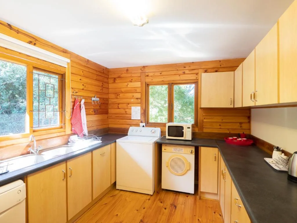 Bright kitchen with yellow cabinetry, washer dryer, and wooden cabin walls