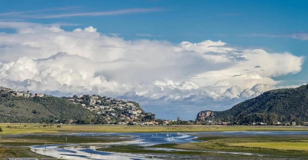 Expansive lagoon view with mountains, sailboats, and dramatic clouds