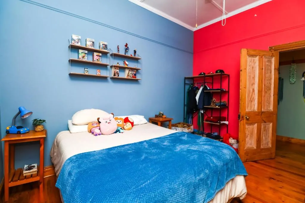 Vibrant child's bedroom with blue bed, colorful walls, and wooden furniture