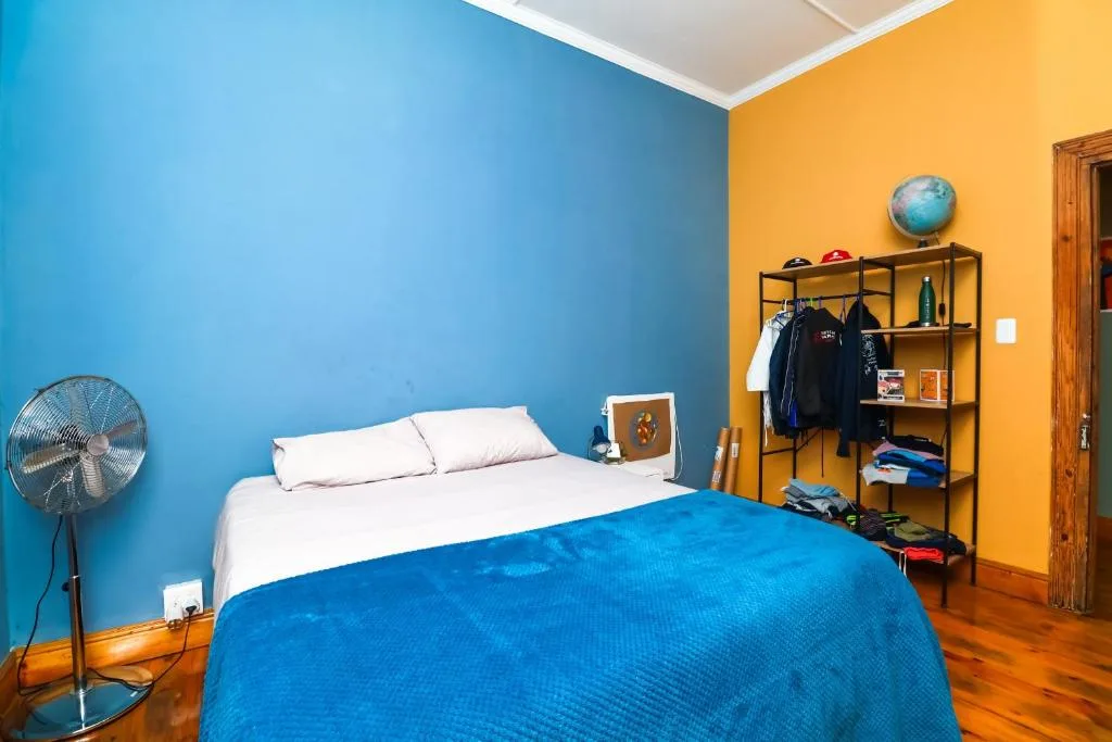 Colorful bedroom with blue bed, white pillows, and yellow accent wall
