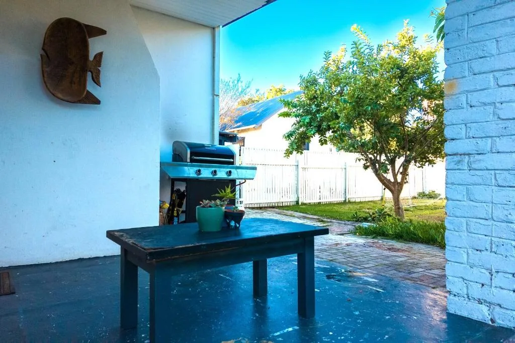 Covered outdoor braai area with table, grill, and garden views
