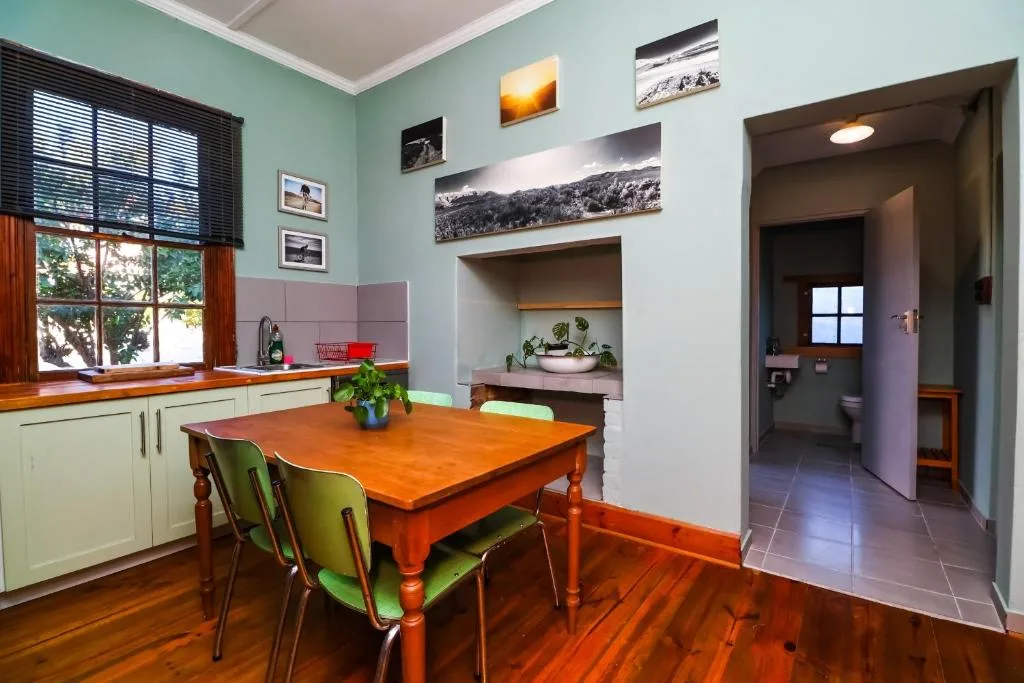 Dining room with wooden table, green chairs, kitchen area visible