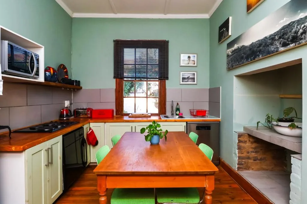 Open-plan kitchen and dining area with wooden table and green chairs