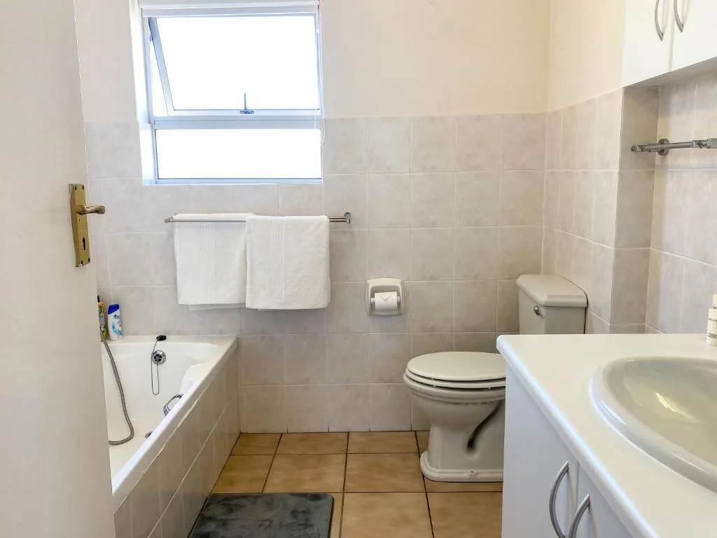 Bright bathroom with bathtub, toilet, and dual sink vanity