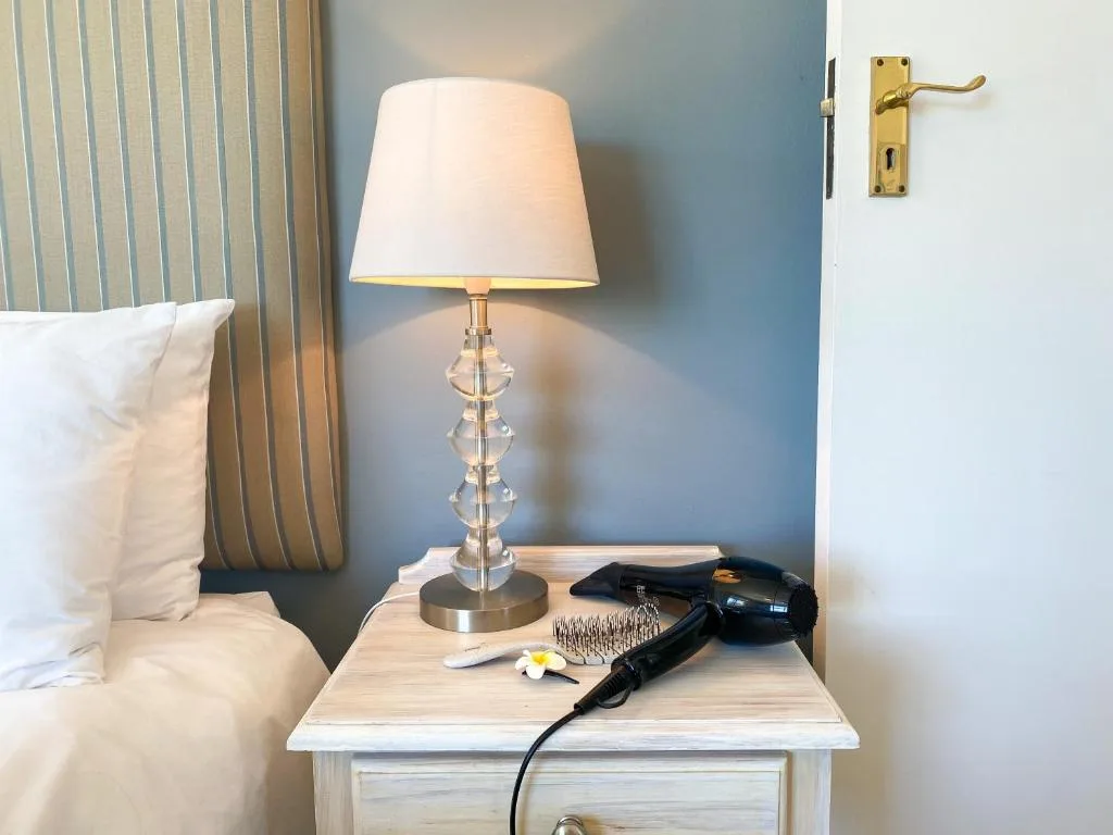 Bedside table with lamp and amenities in modern bedroom space