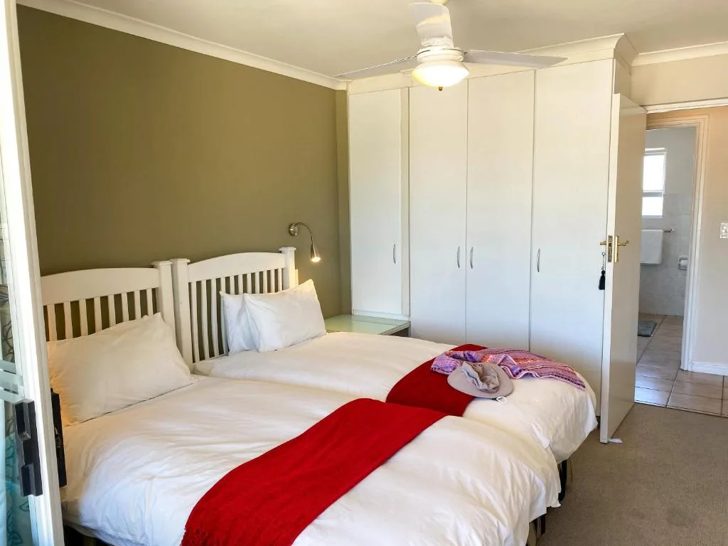 Twin bedroom with white bedding, olive accent wall, and built-in wardrobes