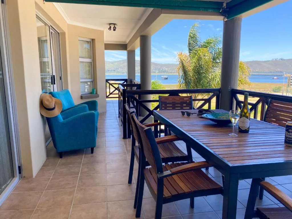Covered patio with dining table, blue chair, ocean and mountain views