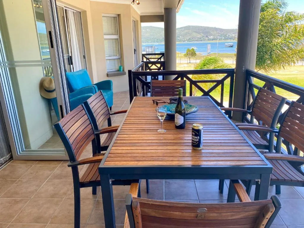 Spacious covered deck with dining table overlooking Knysna Lagoon and mountains