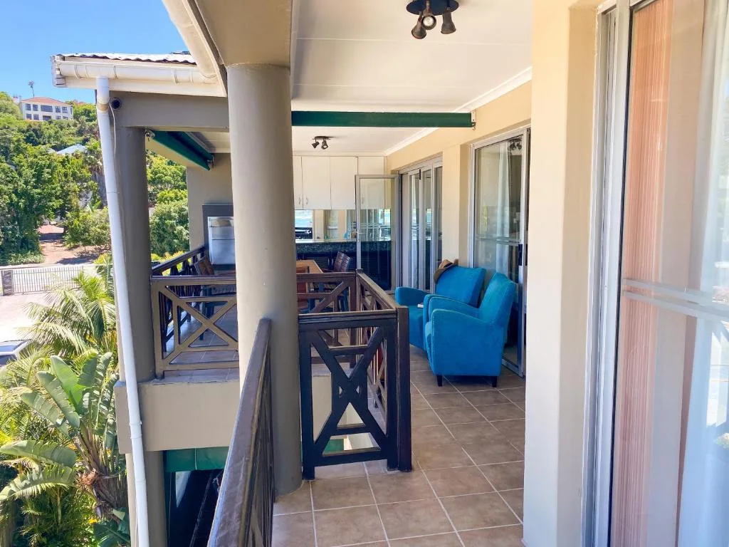 Covered patio with blue armchair, dining table, and garden views