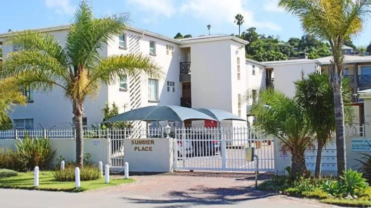 White contemporary apartment building with palm trees and gated entrance