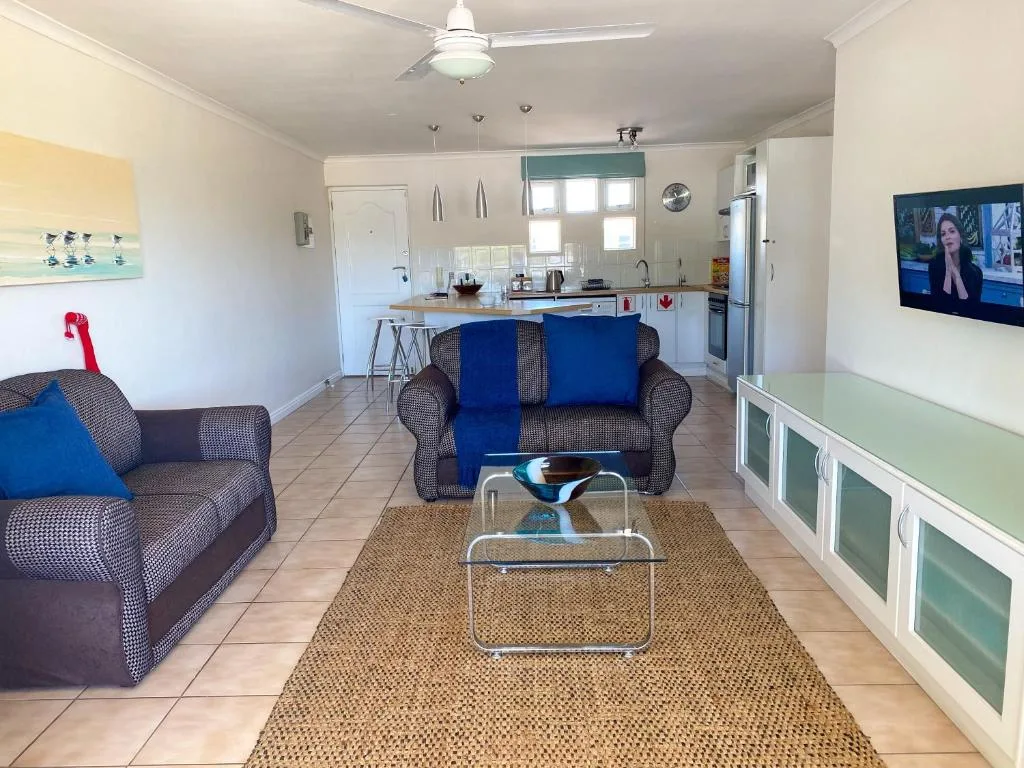 Open-plan living area with blue upholstered sofas and kitchen beyond