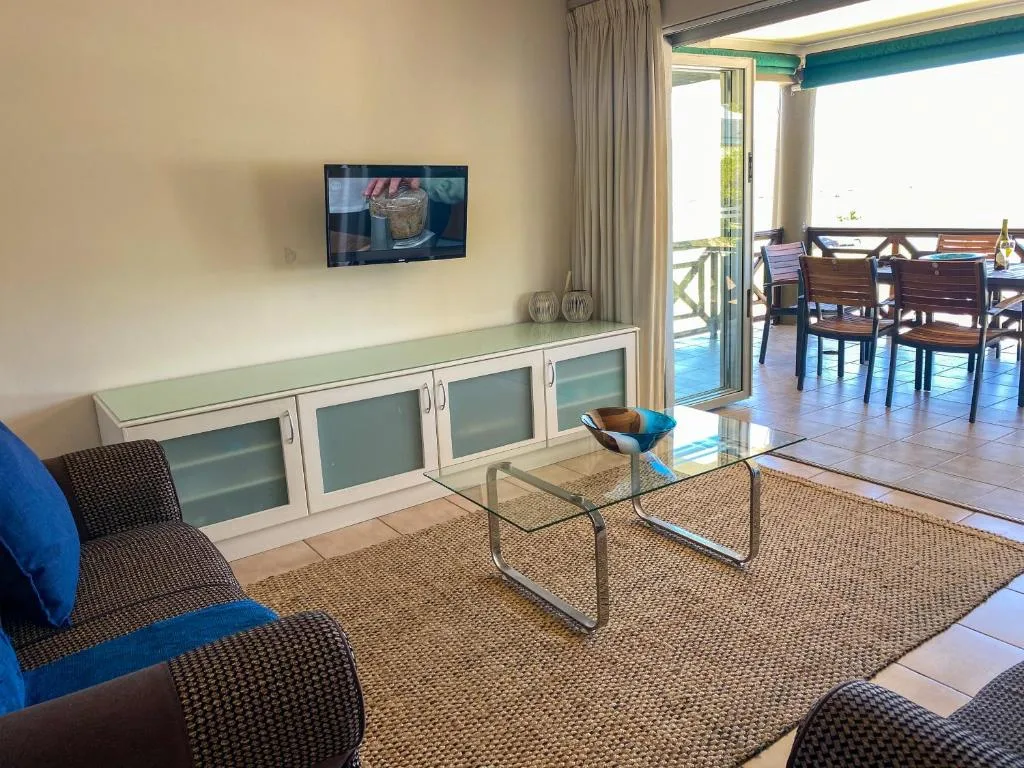 Contemporary lounge with comfortable seating, wall-mounted TV, and glass doors opening to deck