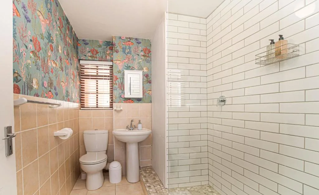Bathroom with toilet, pedestal sink, and shower area with subway tiles