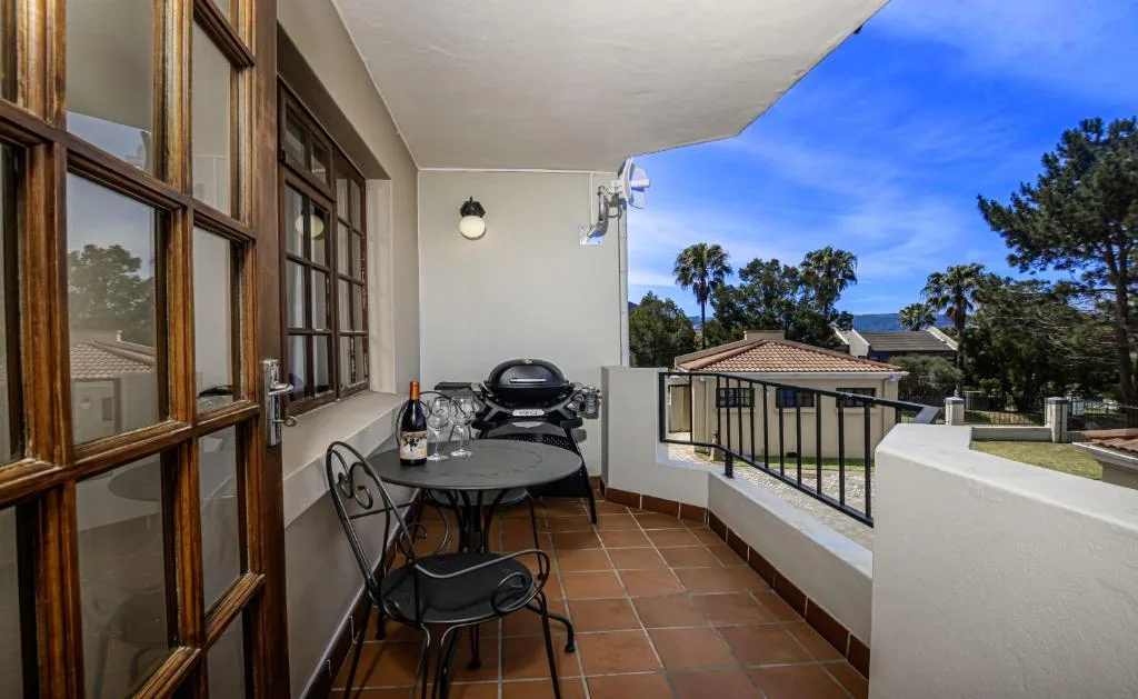 Covered outdoor patio with dining table, braai grill, and mountain views