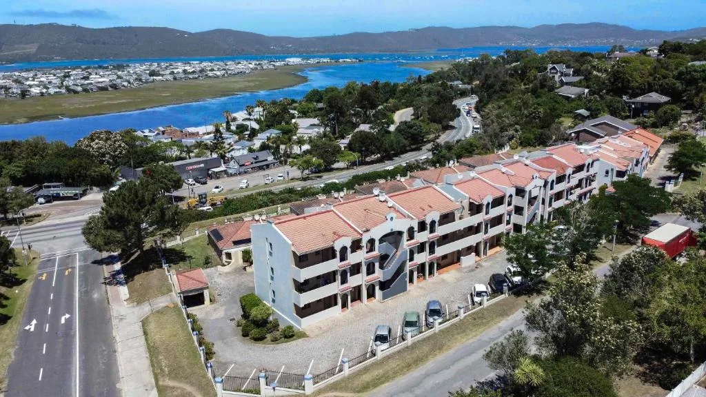 Modern multi-story apartment building with terracotta roof overlooking Knysna lagoon and mountains