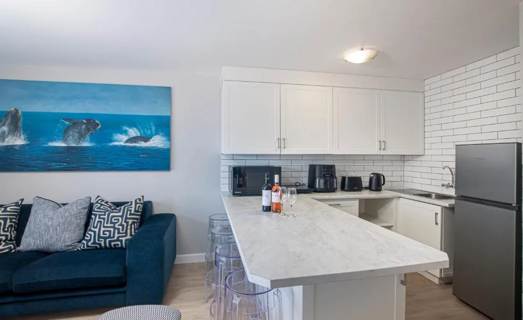 Modern kitchen with white cabinetry, marble countertop, and stainless steel appliances