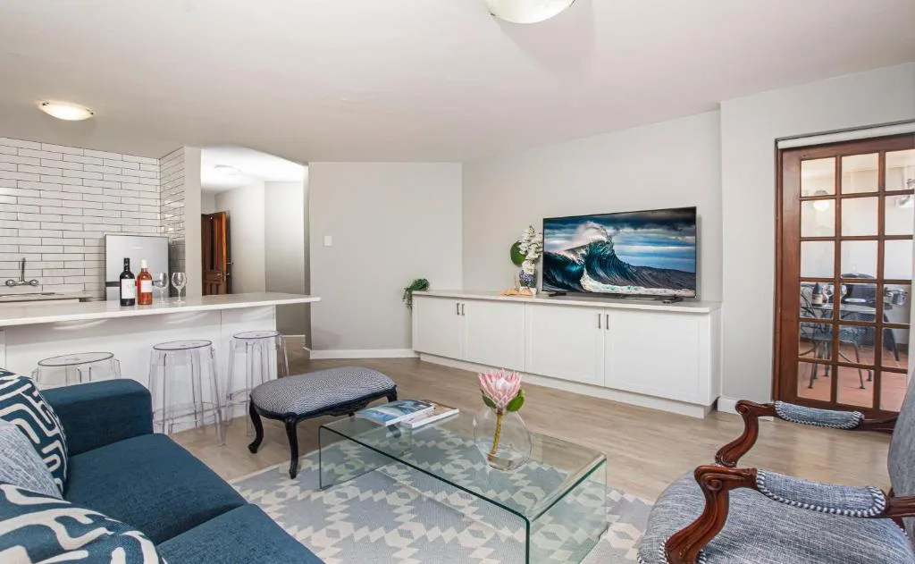 Modern open-plan living room with blue sofa, TV, and kitchen visible