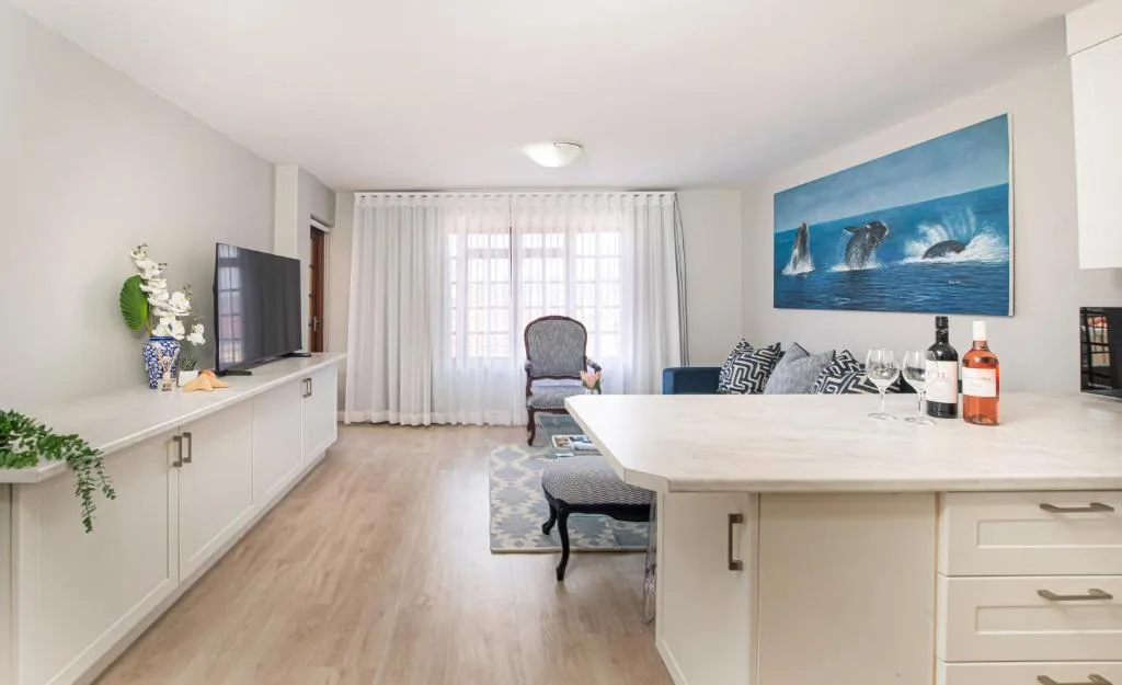 Open-plan lounge with white cabinetry, TV, and ocean artwork