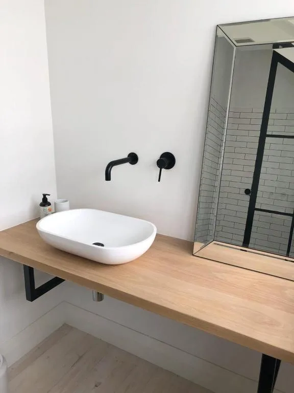 Modern bathroom with white oval sink and black wall-mounted faucet