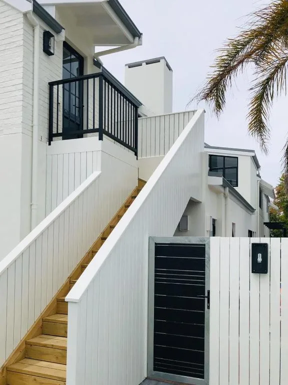 Modern white exterior with wooden staircase and black railing entrance