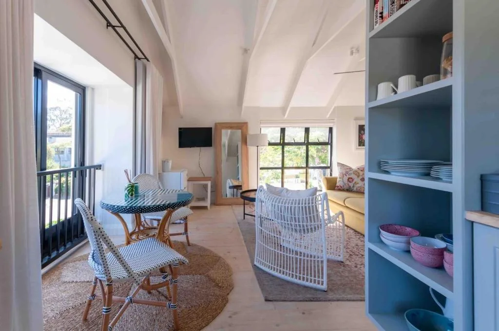 Bright open-plan living area with dining table, sofa, and coastal decor