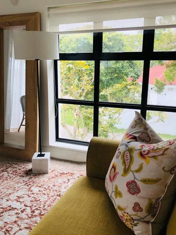 Bright lounge with green armchair, patterned cushion, and garden views through large windows
