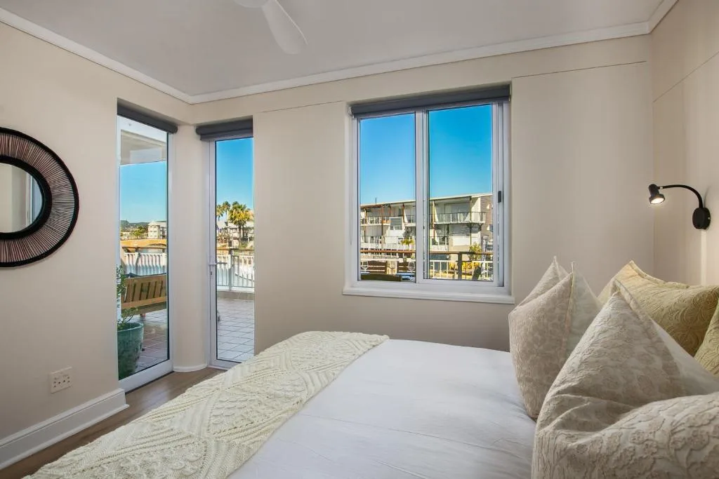 Bright bedroom with bed, waterfront views through glass doors and windows