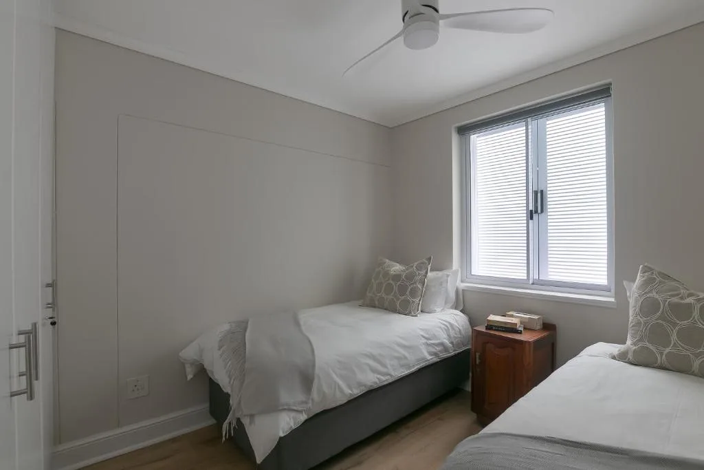 Bright bedroom with two single beds and wooden nightstand near window