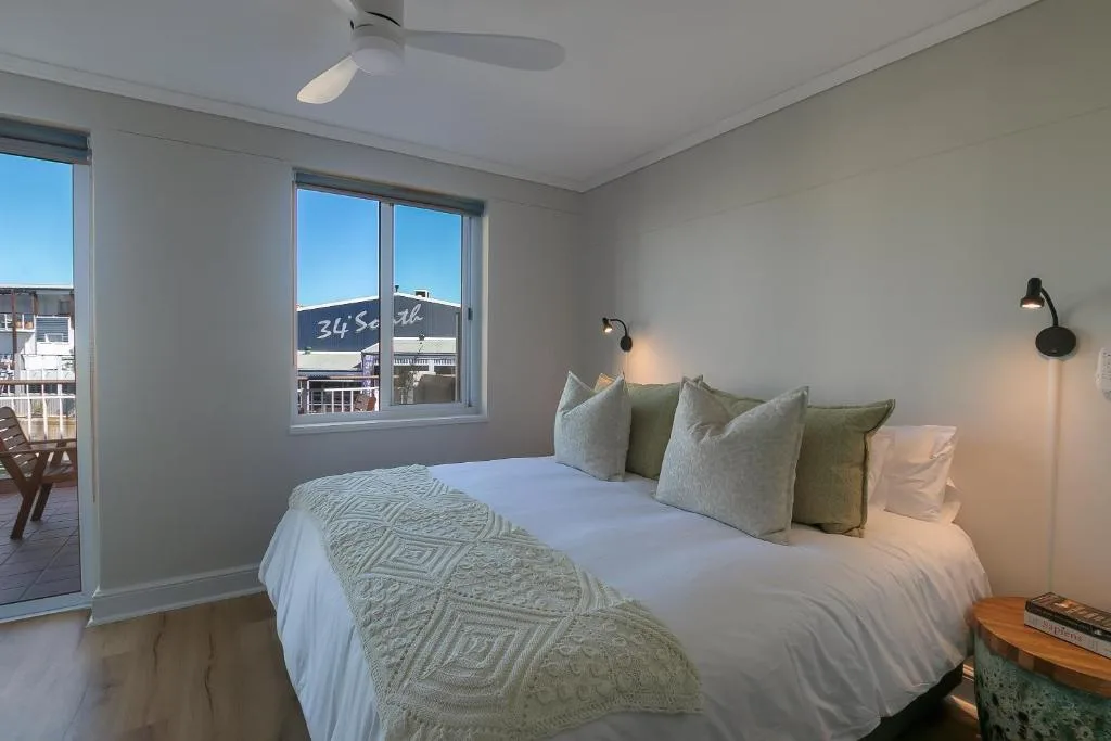 Bright bedroom with queen bed, neutral decor, and waterfront views through large windows