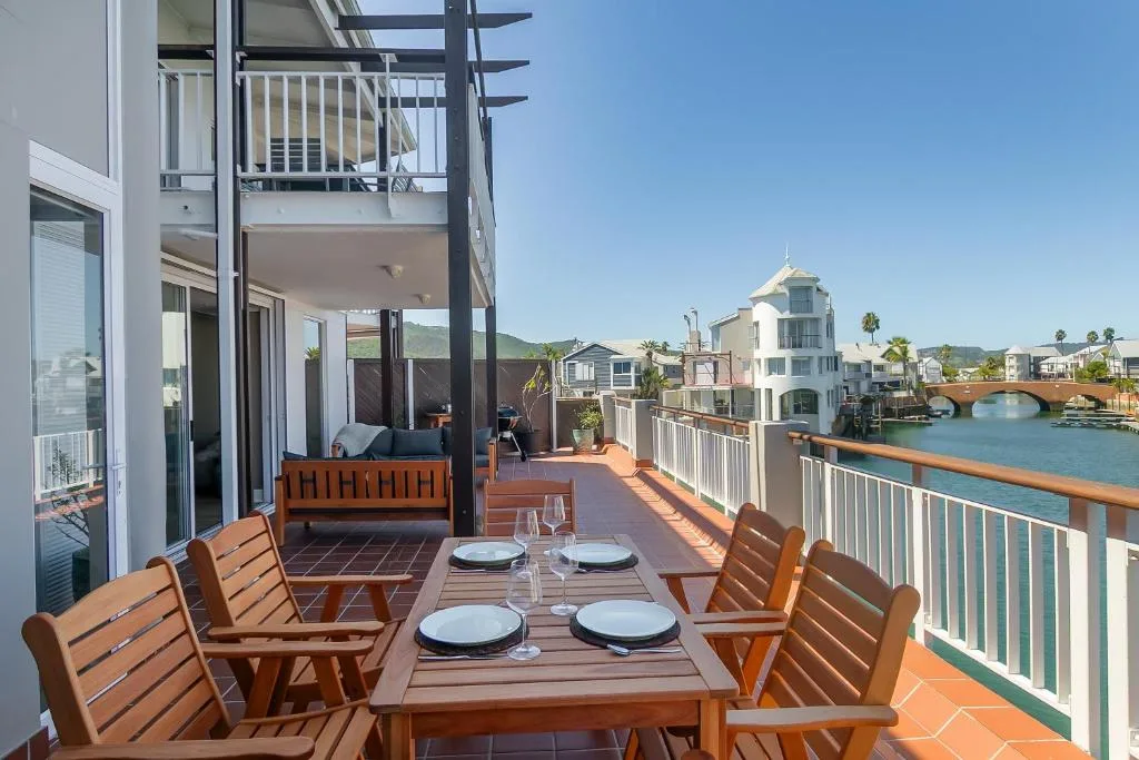 Waterfront deck with dining table overlooking Knysna lagoon and mountains
