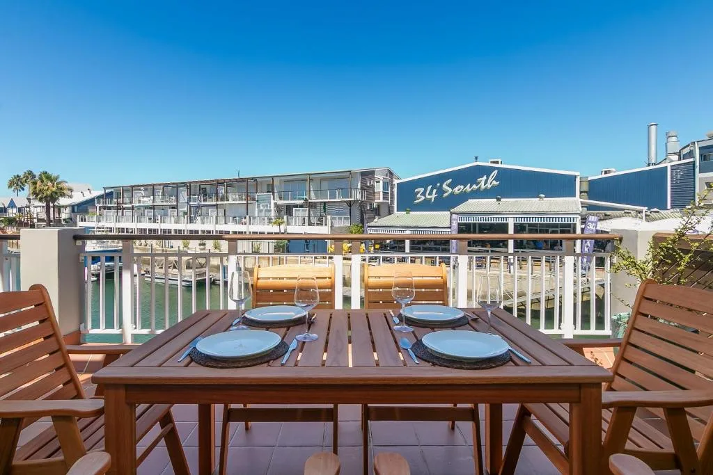 Outdoor dining table set on waterfront deck overlooking Knysna marina