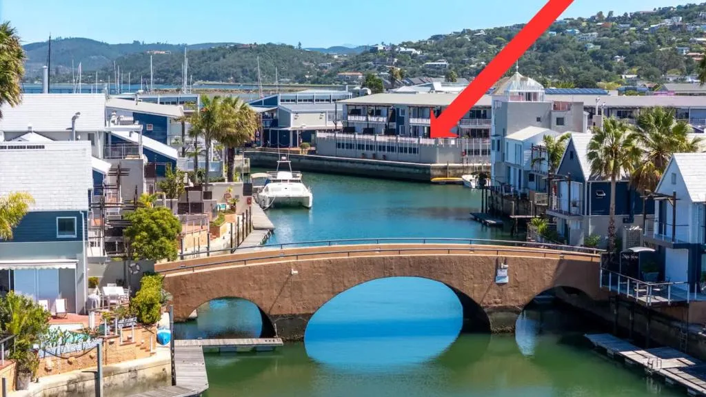 Scenic waterfront vista of Knysna lagoon with bridge, boats, and hillside homes