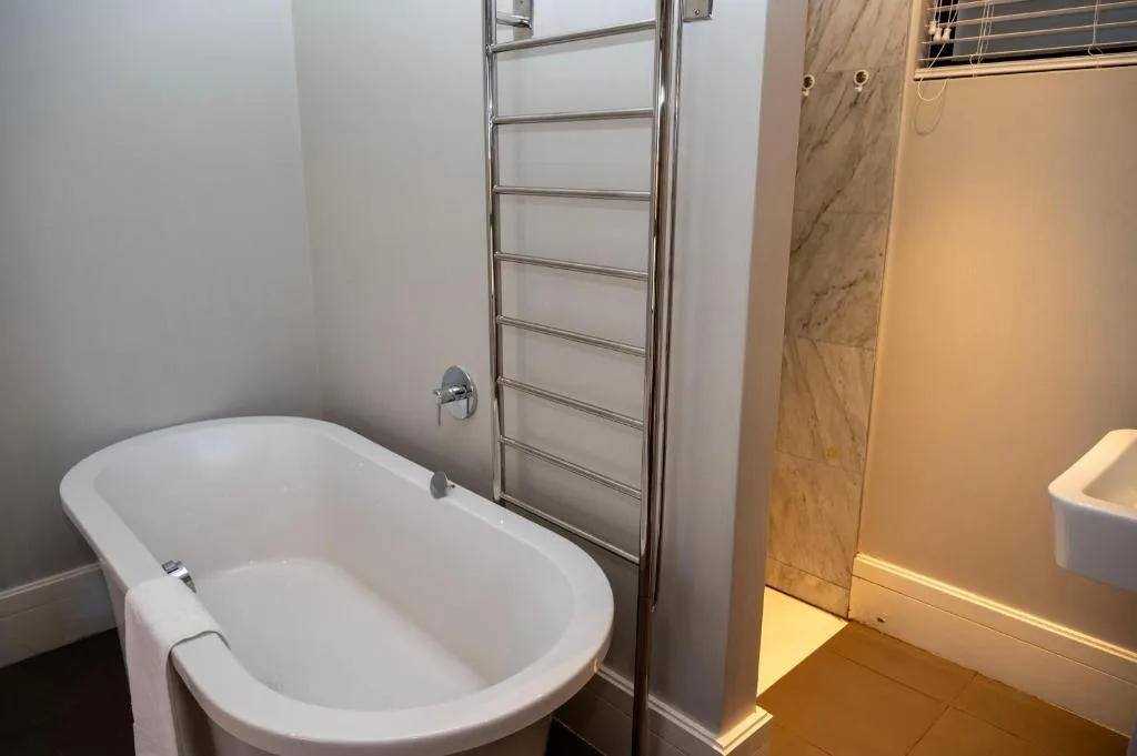 Modern bathroom with freestanding white bathtub and heated towel rack