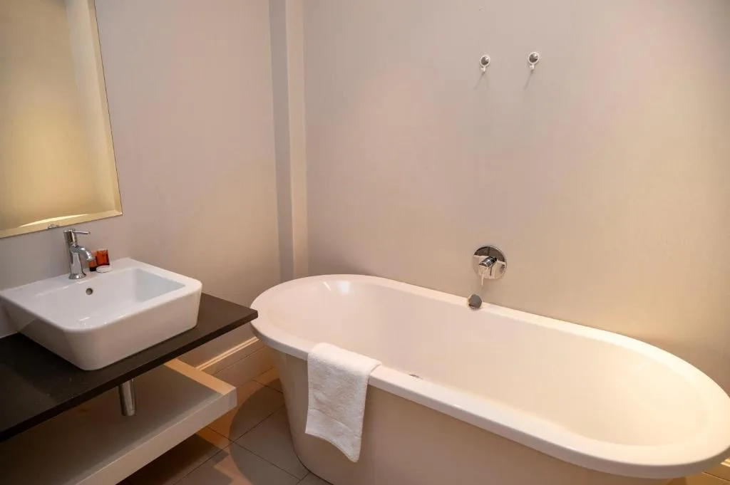 Modern bathroom with freestanding bathtub, square sink, and warm lighting