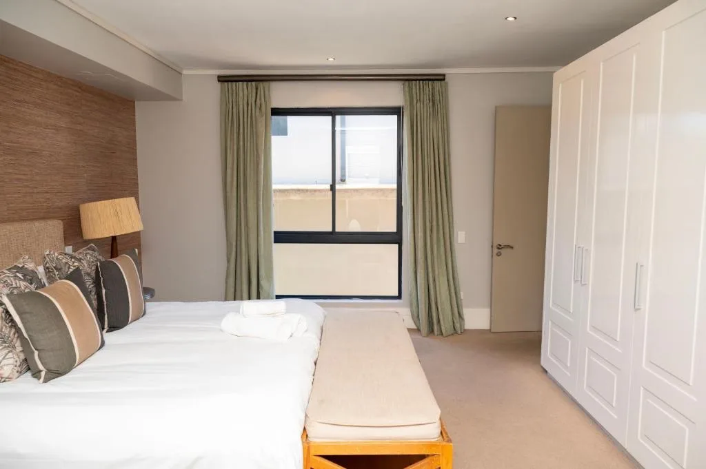 Spacious modern bedroom with double bed, sea view windows, and built-in wardrobe