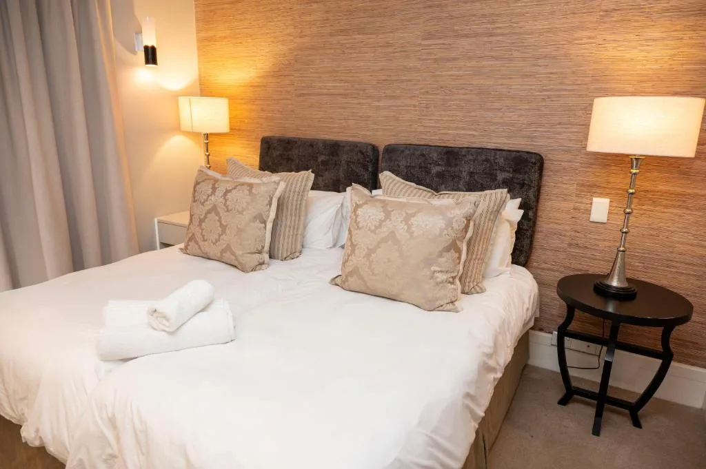 Modern bedroom with queen bed, dark headboard, decorative pillows, bedside lamps