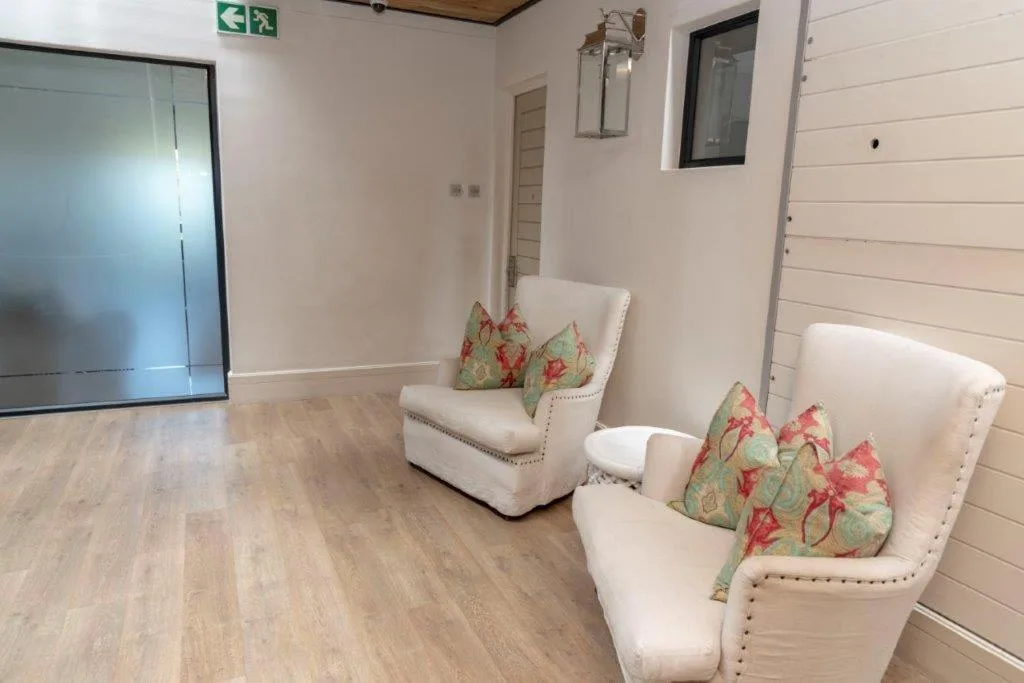 Spacious lounge with two cream armchairs and floral cushions