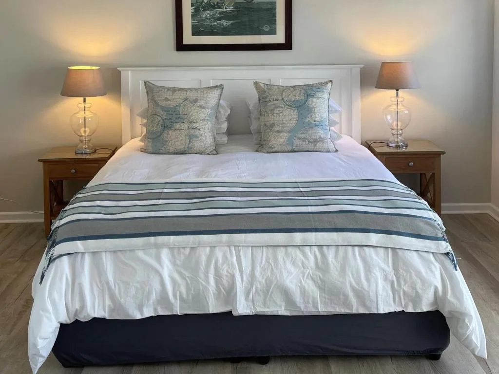 Elegantly styled double bed with map-print pillows and striped throw blanket