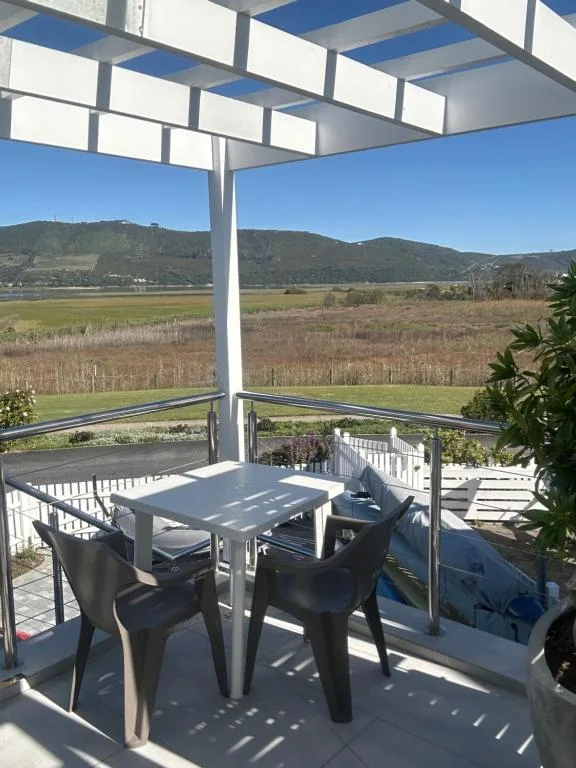Covered outdoor deck with dining table overlooking Knysna valley and mountains