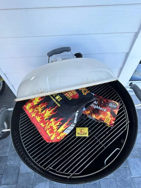 Charcoal braai grill with white dome lid on outdoor patio area
