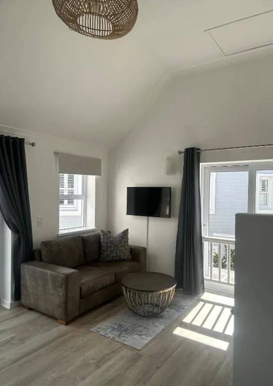 Bright living room with brown sofa, wall-mounted TV, and sliding door access